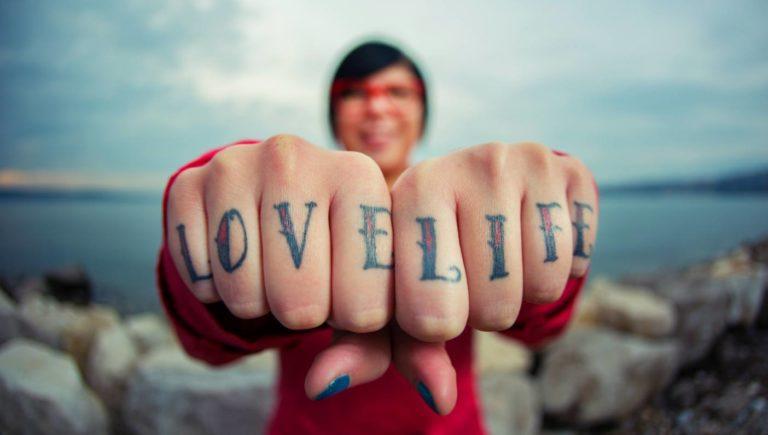 woman showing tattoos on knuckles that say love life