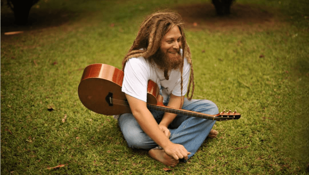 Mike love sitting in grass holding gutar