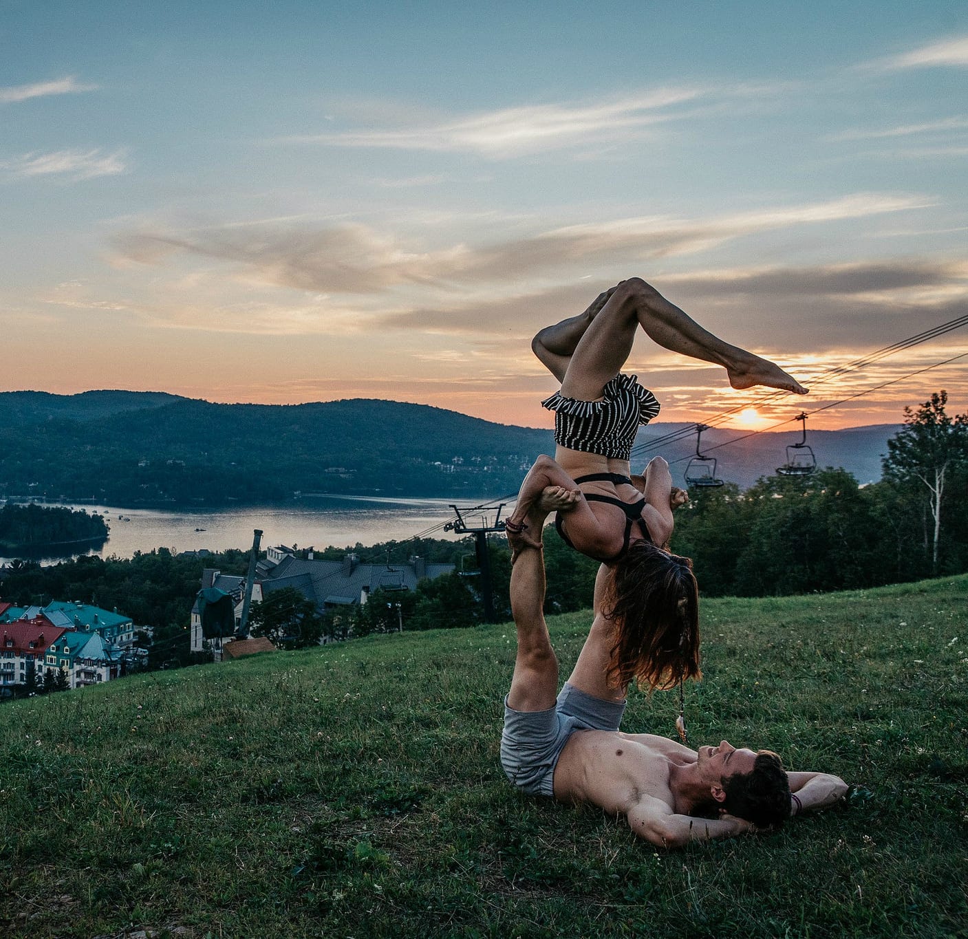 acro yoga on a mountain at sunset with village below