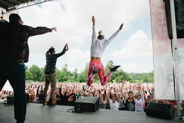 people jumping on stage with large dance party outside