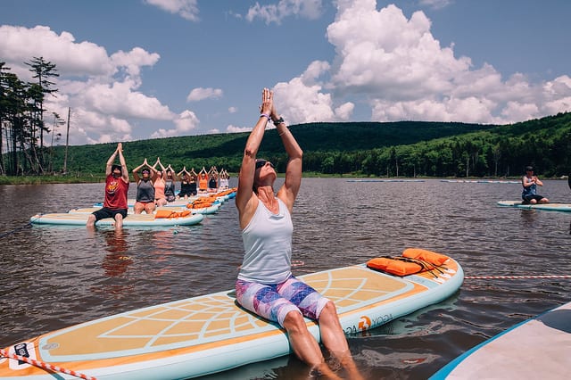 woman on SUP board on lake with class behind her