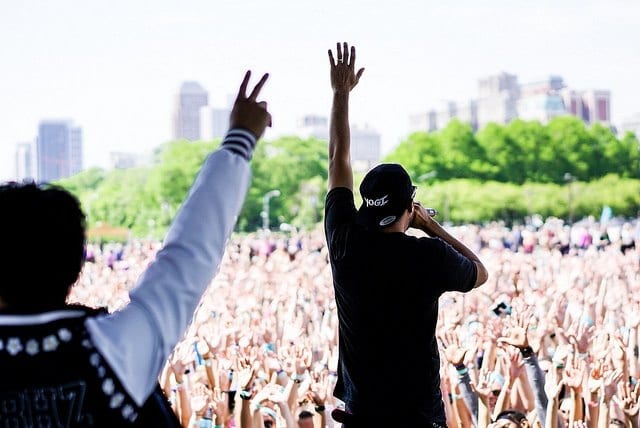 musicians on stage with arms raised playing to large crowd in chicago