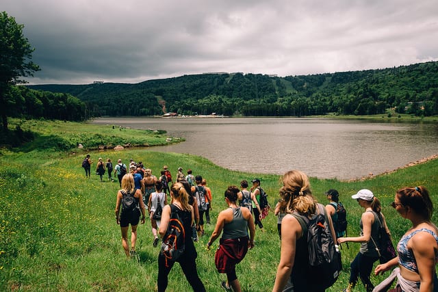 people hiking around lake in green mountain