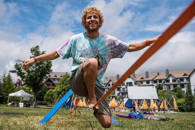 Man on slackline balancing with aireal rigs in background