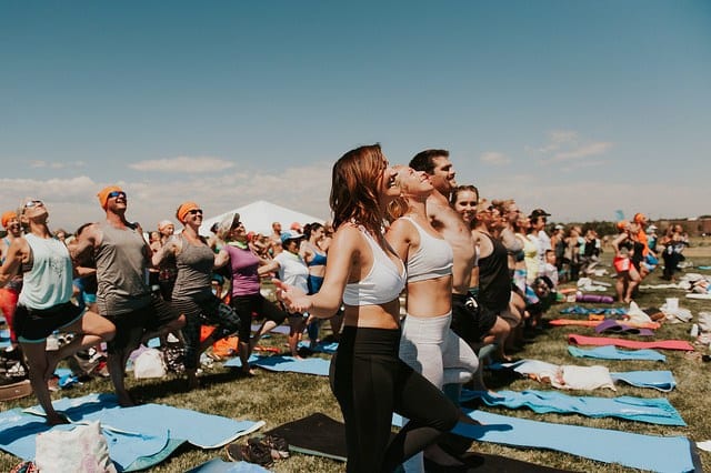 people in crowd doing supported tree pose at yoga festival in denver