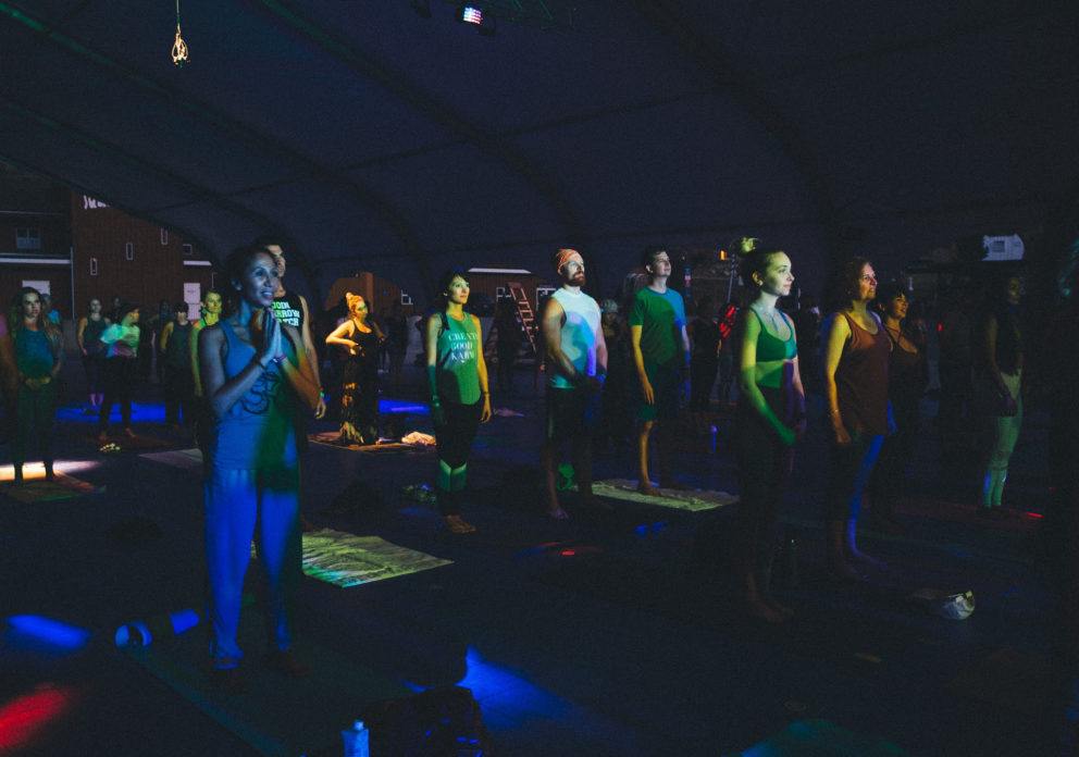 people in dark room with rainbow lights practicing Kundalini yoga