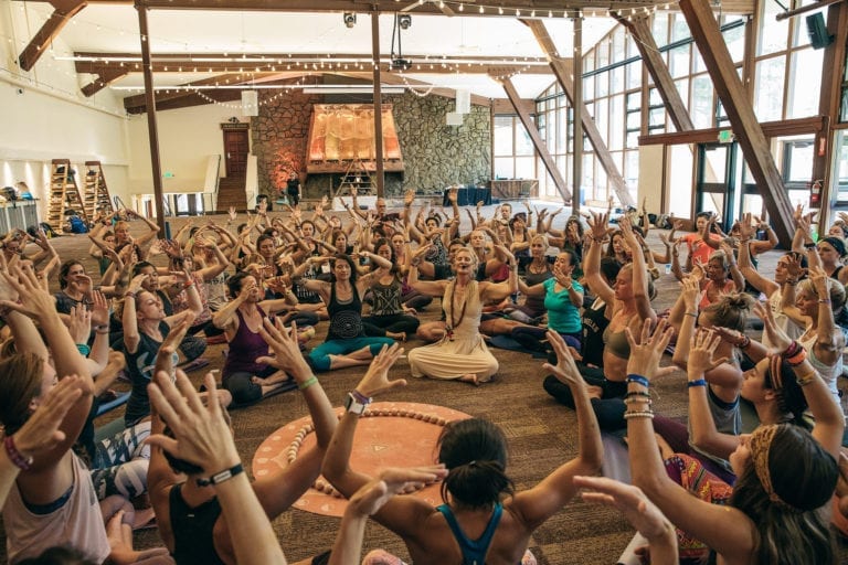 large group of people in meditation class with arms raised