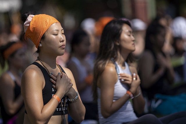 people meditating in field at yoga festival