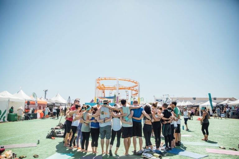 Group of yogis standing together on the Santa Monica Pier. 