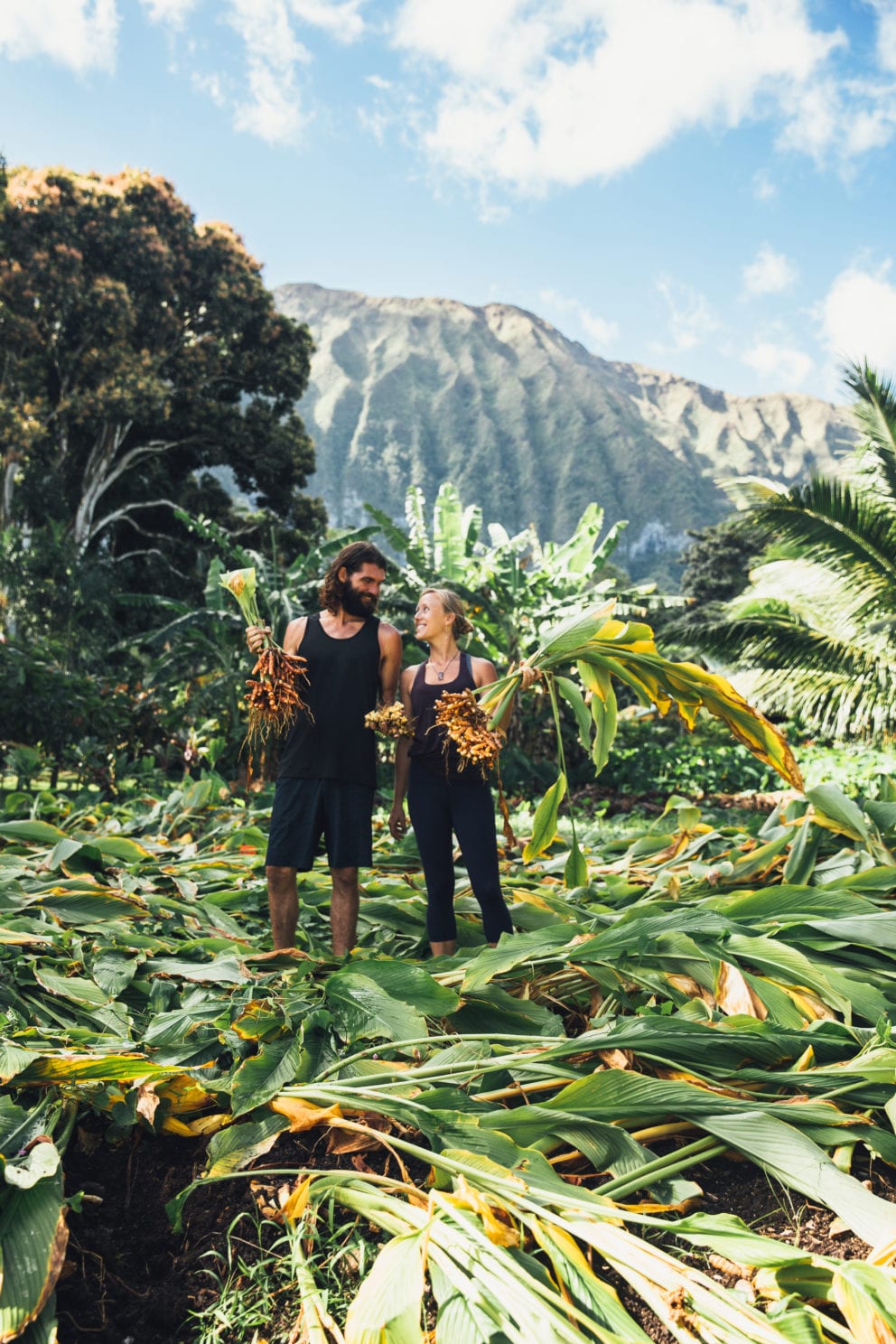 man and woman in Hawaiian farm with mountains in background