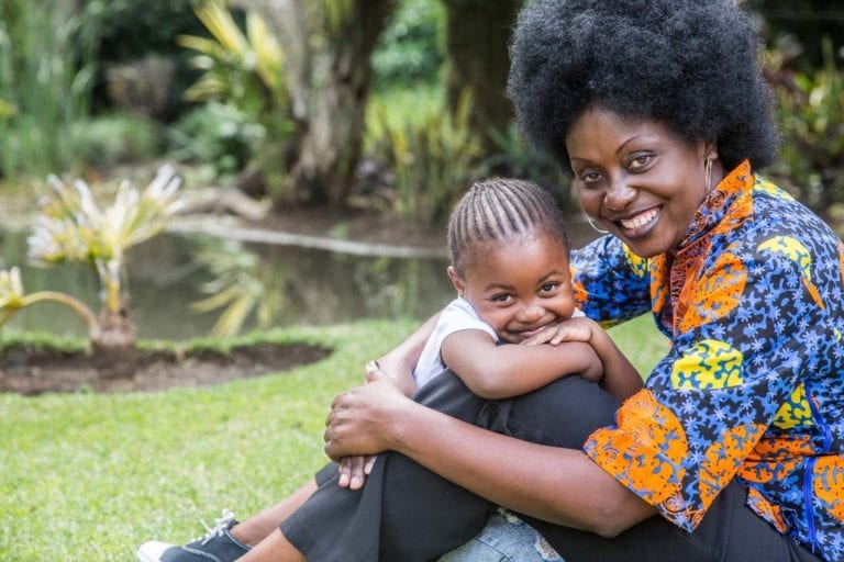 Mother (Connie) holding her daughter, Lubona and smiling. Connie lost three children to AIDS before treatment was available in Zambia. Thanks to life-saving medication, her fourth child Lubona, was born HIV free.