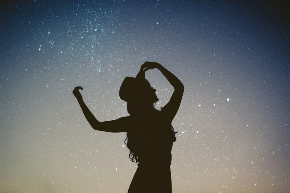 silhouette of woman in fedora against starry night