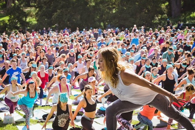 woman teaching yoga on stage to large crowd