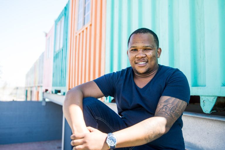 man sitting in front of colorful houses South Africa