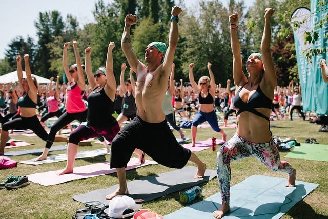 people practicing yoga in large group at festival